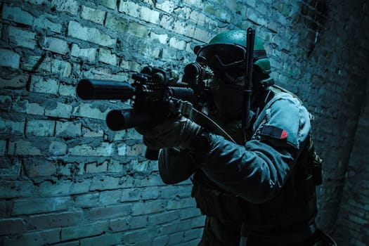 Special forces operator pointing weapon in the dark. Combat helmet, tactical radio system with folding antenna are on. Low key image