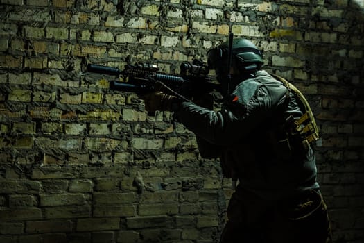 Special forces operator pointing weapon in the dark. Combat helmet, tactical radio system with folding antenna are on. Low key image