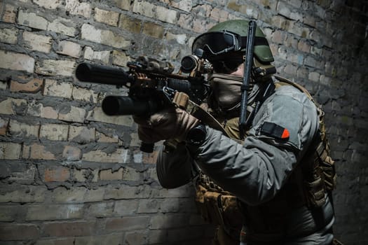 Special forces operator pointing weapon in the dark. Combat helmet, tactical radio system with folding antenna are on. Low key image