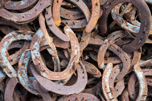 Heap of used and worn rusty Horseshoes outside blacksmith farriers shop or smithy