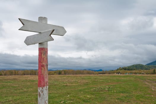 Empty wooden road pointer at cloudy day nature background