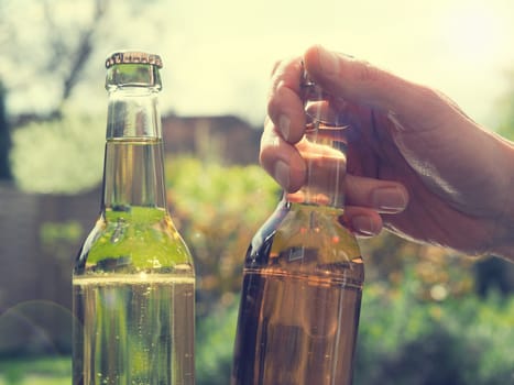 Young man with two bottles of apple juice in the garden