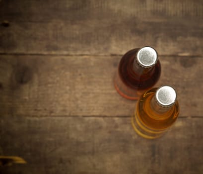 Two bottles of apple juice on an old rustic barn wood background, view from above