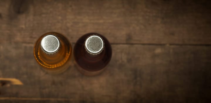 Two bottles of apple juice on an old rustic barn wood background, selective focus from above