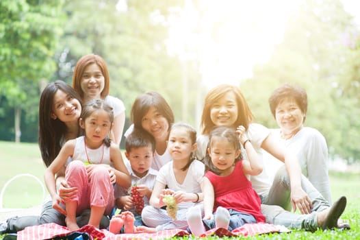 Beautiful Asian multi generations family portrait, grandparent, parents and children, outdoor nature park in morning with sun flare.