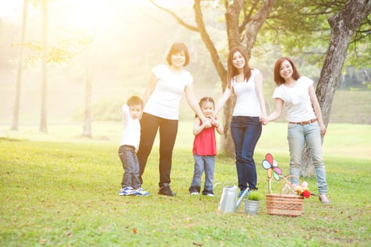 Asian family playing at nature park, parents and children, outdoor in morning with sun flare.