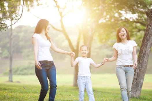 Asian family walking at nature park, outdoor in morning with sun flare.