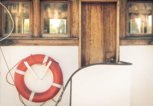 Orange lifebuoy on vintage white boat in port.