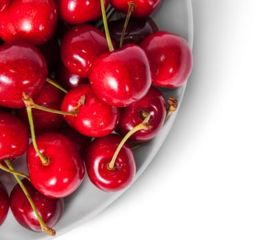 Closeup red sweet cherries in white plate top view isolated on white background