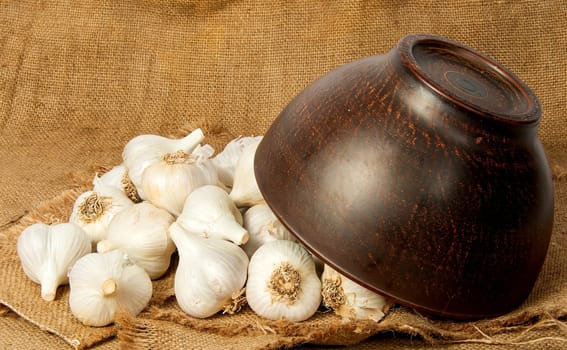 Garlic spill out of a ceramic bowl on sackcloth