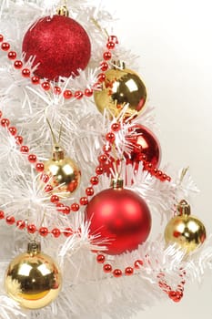 Red and golden decorations are on white Christmas tree.