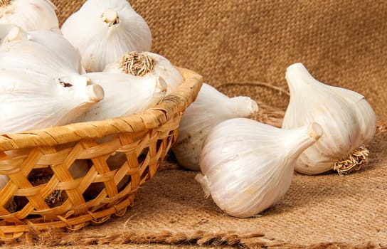 Whole head of garlic in a wicker basket on sackcloth