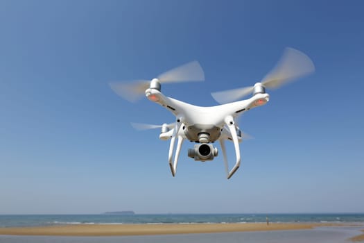 KAGAWA, JAPAN - April 03, 2017: Drone Dji Phantom4 Pro equipped with high resolution video camera hovering in air with beach and clear blue sky in the background