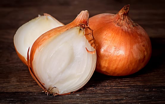 Wholly onion and two halves on a wooden table
