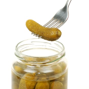 The bottle of pickles and a fork with the cucumber are on white background.