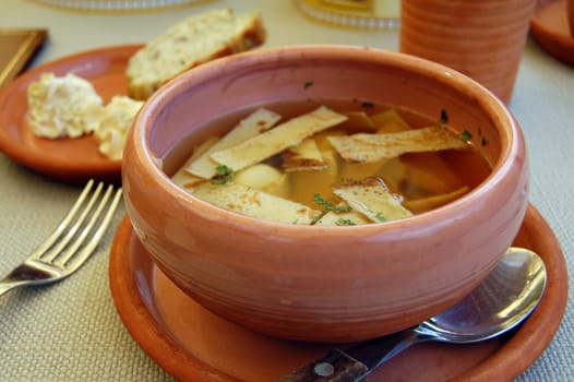 Soup with part of pancakes in earthenware plate.