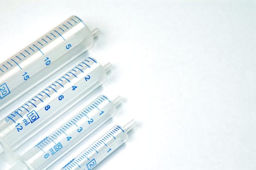 Four syringes in different sizes on white background.