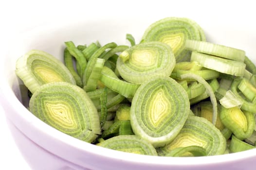Sliced leek is in white plate on white background.