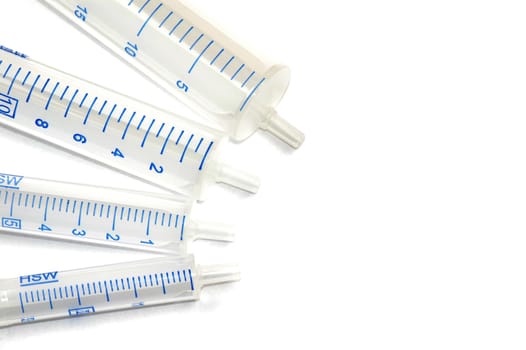 Four syringes in different sizes on white background.