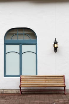 outdoor bench with white wall on brick street