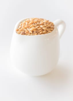 Ceramic pitcher of gold flaxseed, stock photo