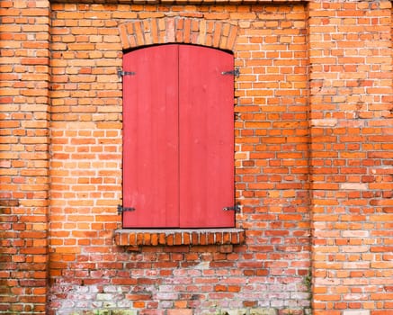 window with red wooden shutters on the brick wall background