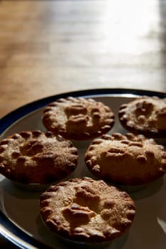 Plate of mince pies shot against the light on a wooden table