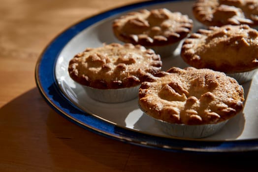 Plate of mince pies shot against the light on a wooden table