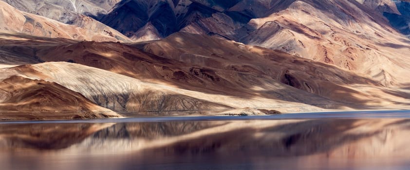 Tsomoriri mountain lake panorama with mountains and blue sky reflections in the lake (north India)