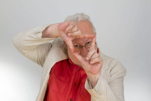 Senior holds hands as a frame in front of his face - on a light background