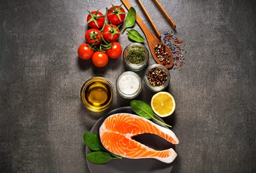 Raw steak of salmon with fresh ingredients on gray background.