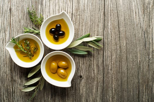 Olive oil with fresh herbs on wooden background