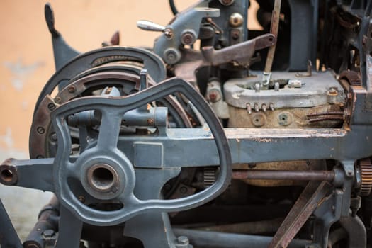 Old rusty printing machine complex mechanism of metal with close up details
