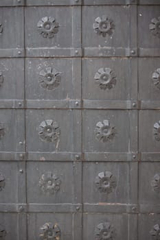 A large massive ancient metal wrought-iron black door with ornamentation