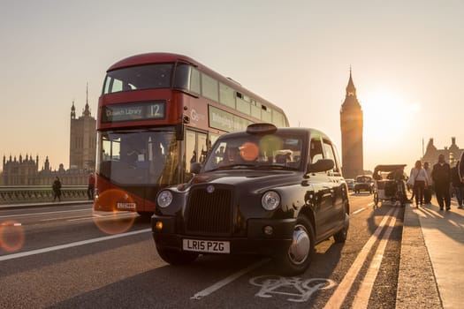 London, UK - April 7, 2015: Traffic and pedestrians passing on Westminster Bridge in sunset on 7th of April, 2017 in London. Big ben and Palace of Westminster aka Houses of Parliament in background.