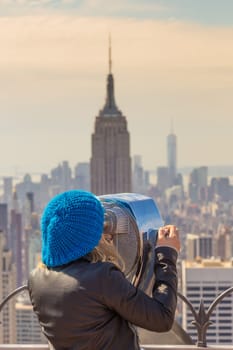 Woman enjoying in New York City panoramic view. Manhattan downtown skyline with illuminated Empire State Building and skyscrapers seen from observation deck terrace.