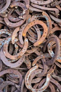 Heap of used and worn rusty Horseshoes outside blacksmith farriers shop or smithy