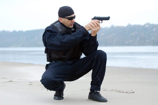 The security man is aiming at something with gun.