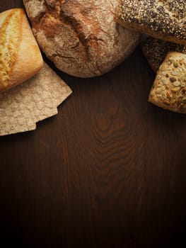 Tasty bread on a rustic wooden background with space for text, view from above