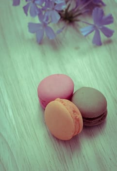 French pink macarons with blue flower on wooden background. Retro-Vintage filter effect