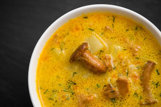 cream soup with mushrooms chanterelles and herbs black stone background,top view