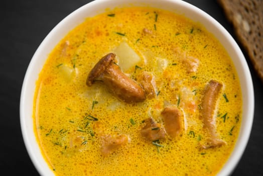cream soup with mushrooms chanterelles and herbs black stone background,top view