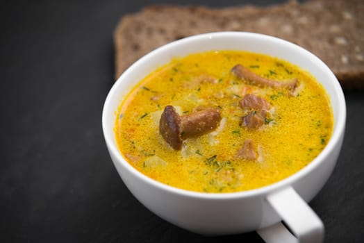 cream soup with mushrooms chanterelles and sunflower bread black stone background