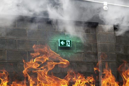 emergency fire exit on the stone wall with fire and smoke