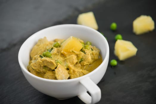 pineapple,pea and pork stew on black stone background