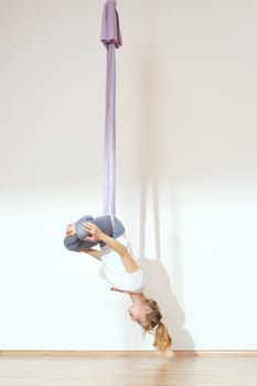 a woman is practicing yoga on a hose,aerial yoga meditation. woman meditating in the position of an inverted lotus flower