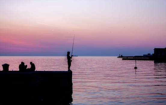 beautiful sunset in Trieste harbor fisherman silhouette on pier