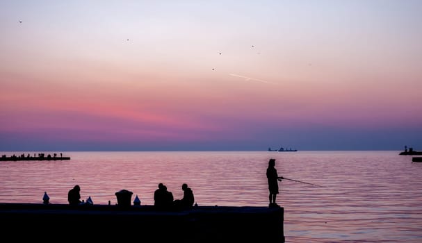 beautiful sunset in Trieste harbor fisherman silhouette on pier