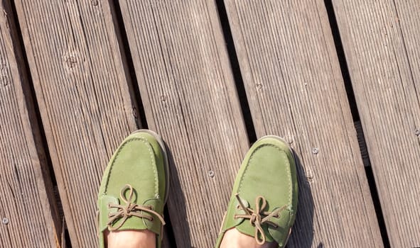 man feet in green top siders standing on wooden floor
