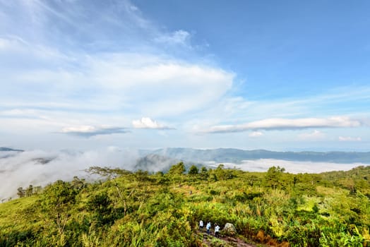 Tourists are walking on nature trails amidst the beautiful landscape of mountain range sky cloud and fog in the winter at Phu Chi Fa Forest Park, Chiang Rai Province, Thailand